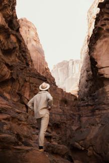 a man in a hat walking through a canyon by NEOM courtesy of Unsplash.