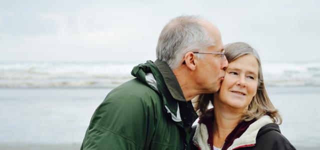 man kissing woman on check beside body of water by Esther Ann courtesy of Unsplash.